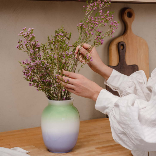 Rosa Blüten in farbiger Rosenthal Vase werden in der Küche arrangiert